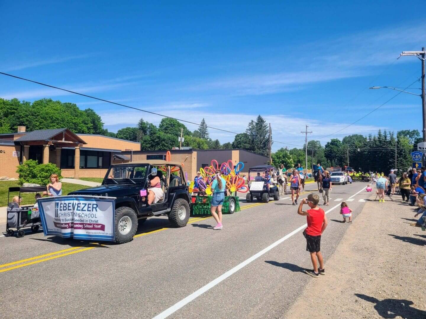 Parade with decorated vehicles and people enjoying a sunny day.